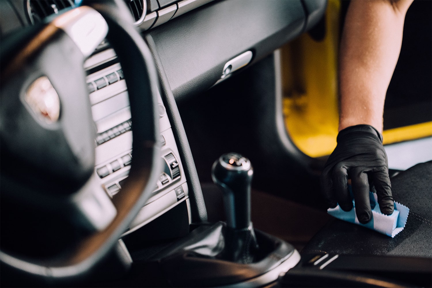 A RestorFX Technician protecting the leather console of a yellow sports car with ClearFX Interior product