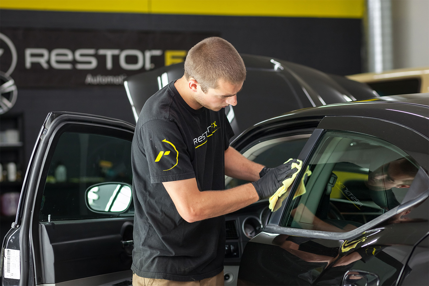 A RestorFX Technician wiping off the plastic trim of a car door as part of restoring it