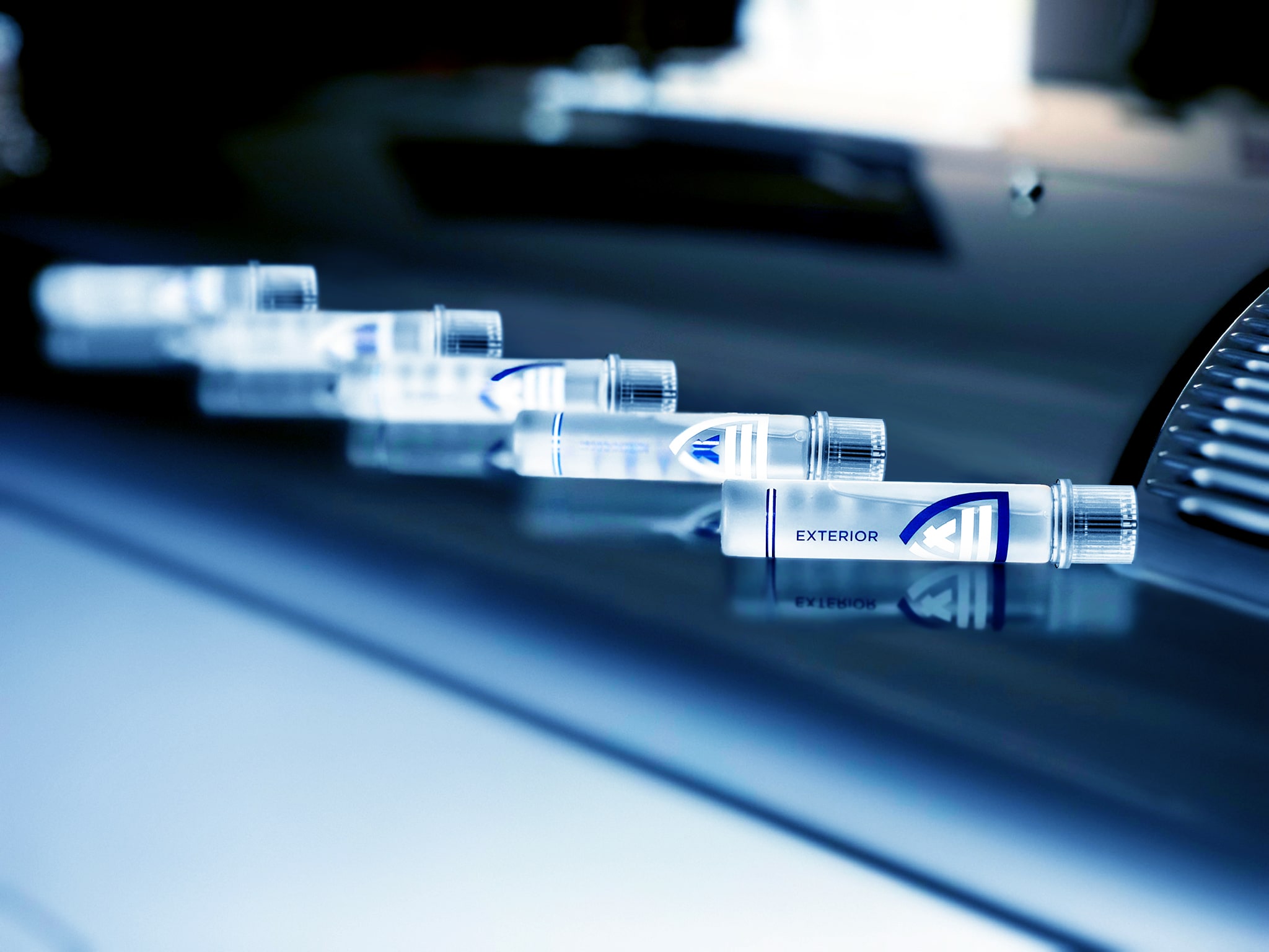 Crystal-clear ClearFX product bottle variants on the hood of a blue vintage 1976 Mercedes Benz 500 SL Coupe